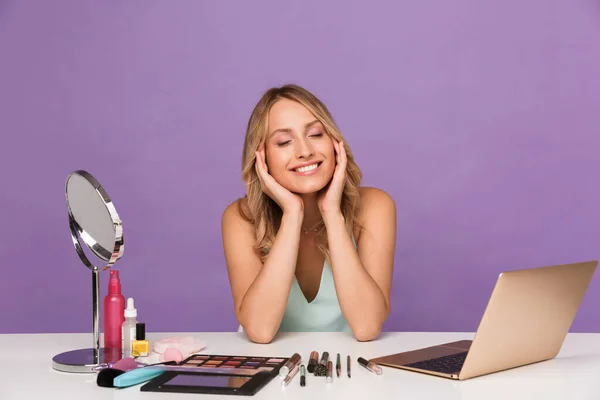 Зображення щасливої мрії жінки, яка використовує ноутбук під час макіяжу — стокове фото