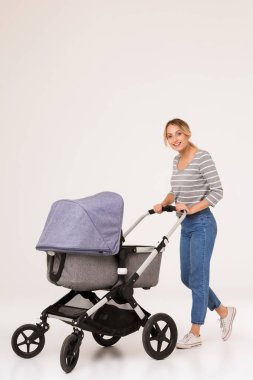 Sarışın kadın anne bebek arabasında bebekle yürüyor.