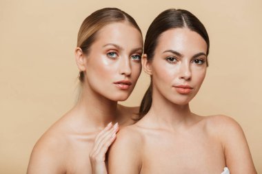 Bej duvar arkasında çıplak poz veren kadınlar.