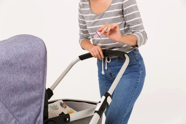 Cropped image of caucasian woman giving pacifier her baby in pram — Stock Photo, Image