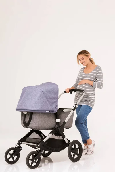 Beauituful young woman standing with a baby pram — Stock Photo, Image