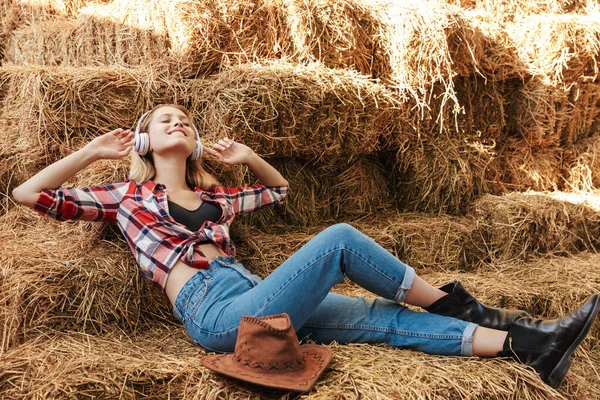 笑顔若いですブロンドカウガール座っています上のA haystackでザ納屋 — ストック写真