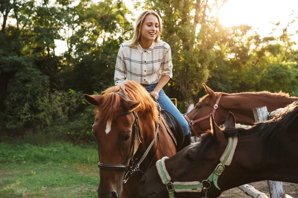 Sorrindo atraente jovem loira menina montando um cavalo — Fotografia de Stock