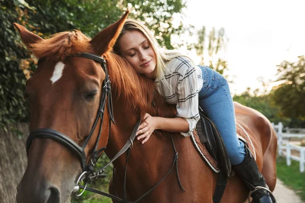 Улыбающаяся привлекательная молодая блондинка верхом на лошади — стоковое фото