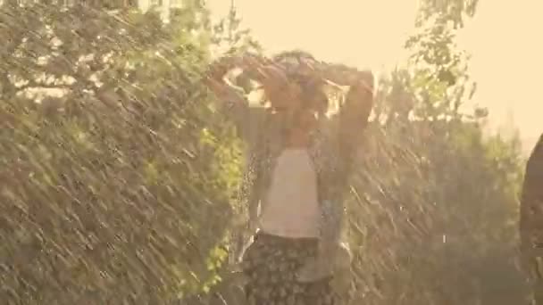 興奮した若いブルネットの女性はスプリンクラーの近くにジャンプし 公園で楽しみながら濡れる — ストック動画