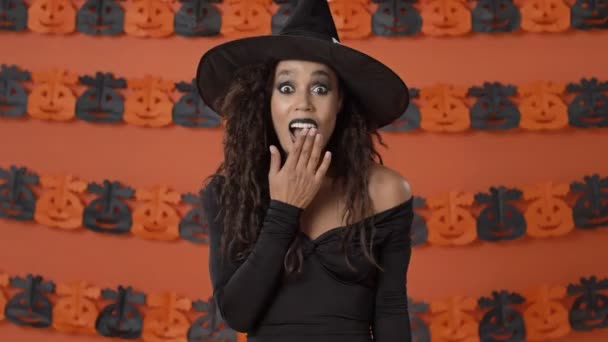 Удивлённая Веселая Молодая Колдунья Чёрном Костюме Хэллоуин Закрывает Рот Руками — стоковое видео