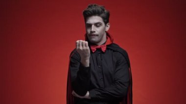 Sivri dişli, cadılar bayramı kostümlü hoşnutsuz vampir bir şeyden korkuyor ve kenara atlıyor.