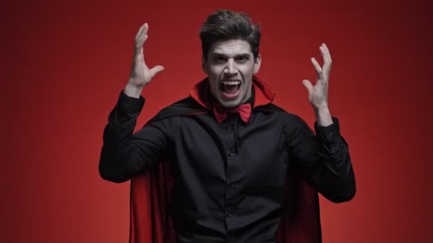 吸血鬼男とともに血と牙で黒ハロウィンコスチュームタッチ彼の頭と悲鳴のために取得悪いニュース絶縁以上赤壁 — ストック動画