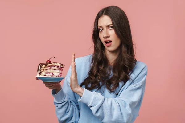 Obraz Niezadowolonej Brunetki Wykonującej Gest Odmowy Trzymającej Kawałek Ciasta Różowym — Zdjęcie stockowe