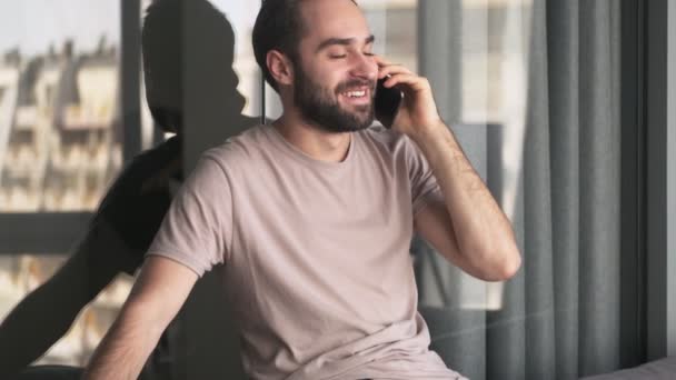 Joven Guapo Está Hablando Teléfono Inteligente Sentado Casa Sala Estar — Vídeo de stock