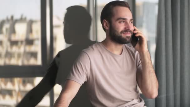 Usmívající Mladý Muž Mluví Svém Smartphonu Sedí Doma Obývacím Pokoji — Stock video