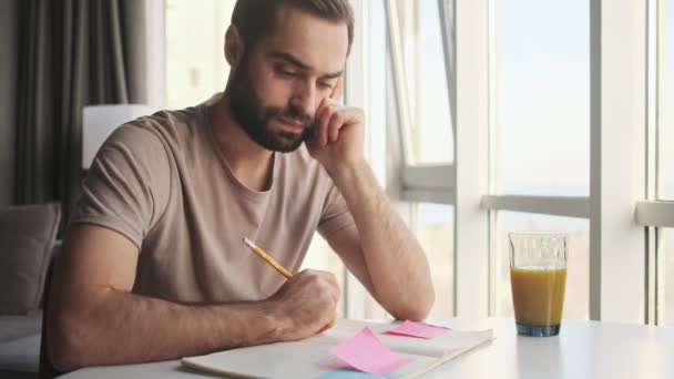 Joven Serio Está Tomando Notas Sentado Mesa Casa — Vídeos de Stock