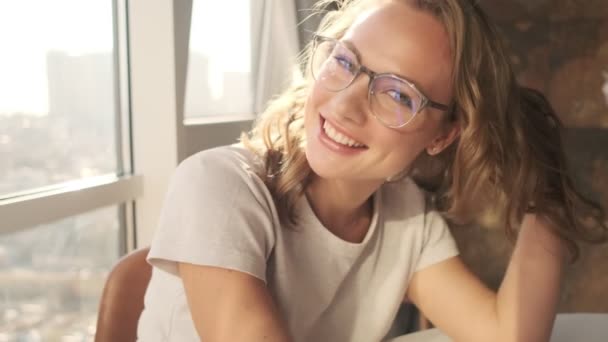 Jonge Optimistische Vrouw Binnen Met Een Bril Bij Het Raam — Stockvideo