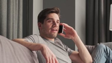 Evde cep telefonuyla konuşan konsantre olmuş genç bir adam.