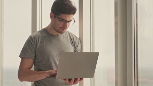 Homem Concentrado Dentro Casa Olhando Para Janela Usando Computador Portátil — Vídeo de Stock