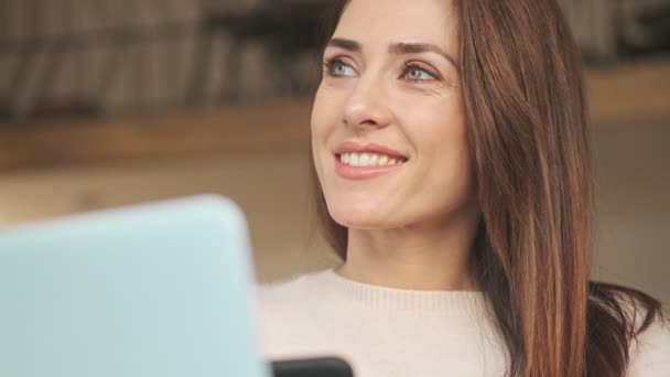 美しい若い女性がカフェ内に座ってコーヒーを飲みながらコーヒーを飲んでいる — ストック動画