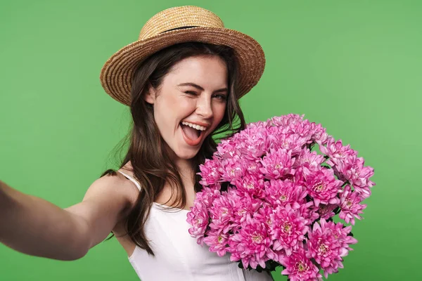 Imagen Mujer Alegre Sombrero Paja Sosteniendo Flores Mientras Toma Foto —  Fotos de Stock