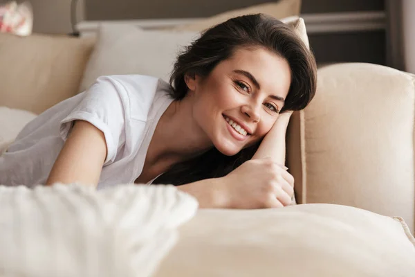 Mooie Glimlachende Jonge Brunette Vrouw Ontspannen Een Bank Thuis Kijken — Stockfoto