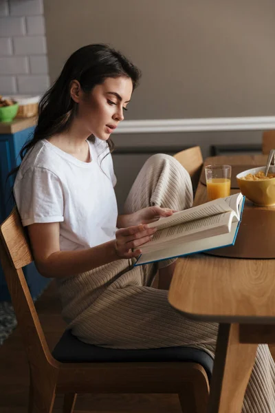 Atraktivní Mladá Brunetka Žena Zdravou Snídaní Čtení Knihy Zatímco Sedí — Stock fotografie