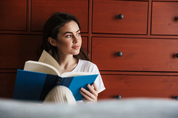 Jovem Morena Sorridente Atraente Lendo Livro Enquanto Senta Chão Inclina — Fotografia de Stock