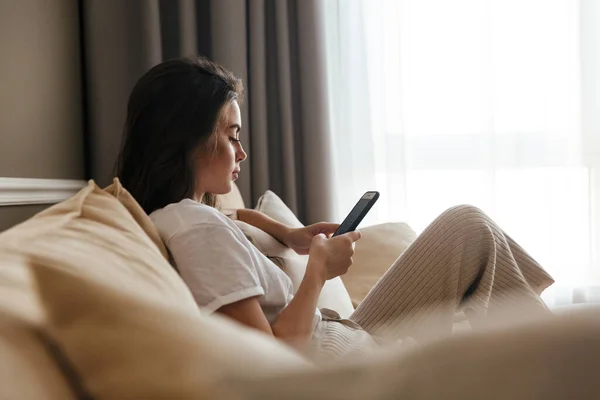 Hermosa Mujer Morena Joven Relajándose Sofá Casa Uno Usando Teléfono — Foto de Stock