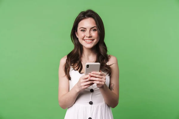 照片中快乐迷人的女人笑着用绿色背景隔离的手机 — 图库照片