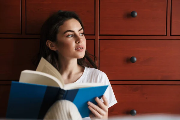 Çekici Gülümseyen Esmer Bir Kadın Yerde Oturmuş Kitap Okuyor Bir — Stok fotoğraf