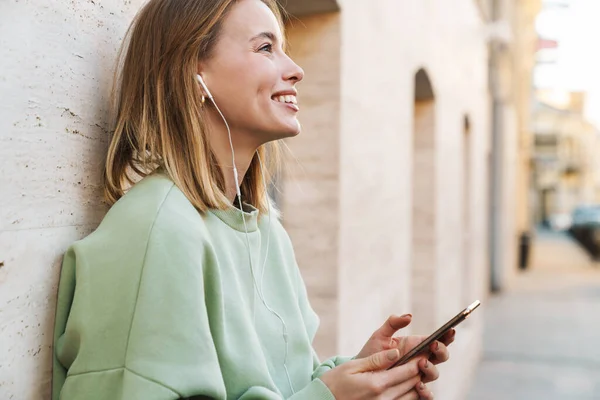 Retrato Una Joven Sonriente Usando Auriculares Teléfono Móvil Mientras Camina — Foto de Stock