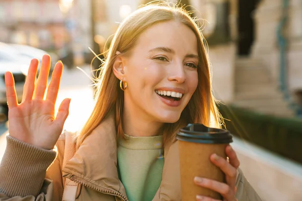 Portrét Radostné Bělošky Mávající Rukou Popíjející Kávu Při Chůzi Ulici — Stock fotografie