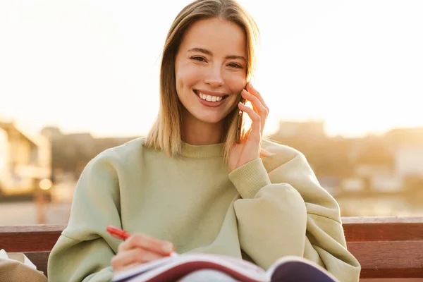 Dışarda Bankta Otururken Cep Telefonu Kullanan Egzersiz Kitaplarıyla Çalışan Gülümseyen — Stok fotoğraf