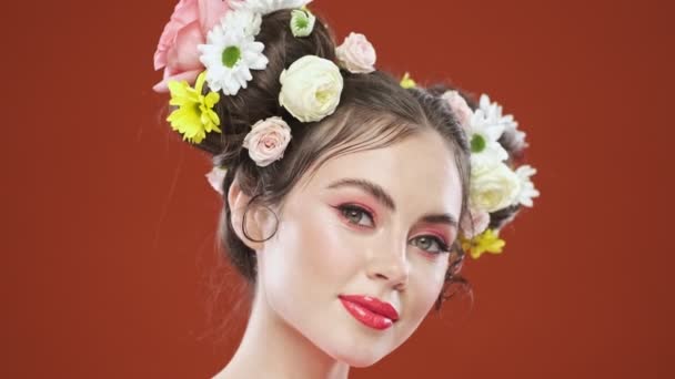 Красивая Молодая Брюнетка Удивительной Цветочной Прической Позирует Красном Фоне Студии — стоковое видео