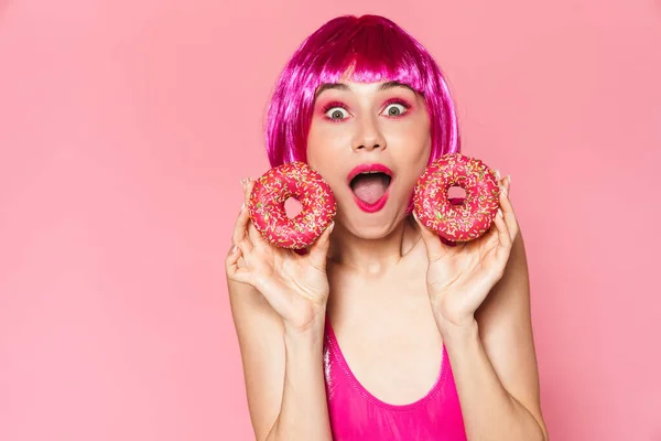 Изображение Девушки Вечеринки Парике Улыбающейся Держащей Пончики Розовом Фоне — стоковое фото