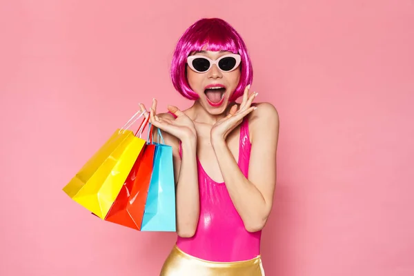 照片中 兴奋的女孩戴着假发和太阳镜尖叫着 提着粉色背景的购物袋 — 图库照片