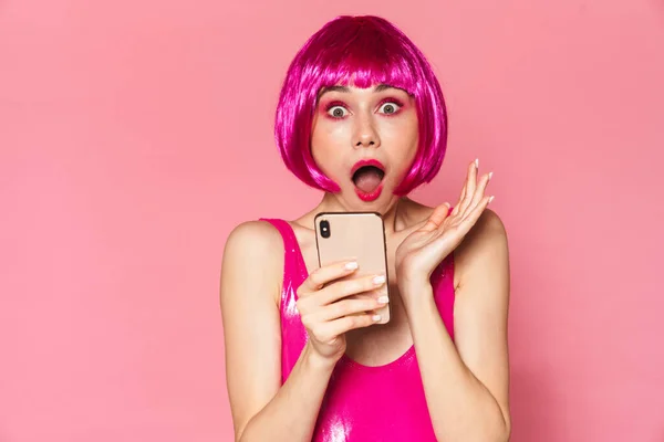Wizerunek Imprezowiczki Peruce Wyrażającej Zaskoczenie Korzystającej Telefonu Komórkowego Odizolowanego Różowym — Zdjęcie stockowe