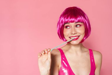 Pembe arka planda izole edilmiş marmelatı gererken peruk takmış gülümseyen neşeli güzel kadın görüntüsü.