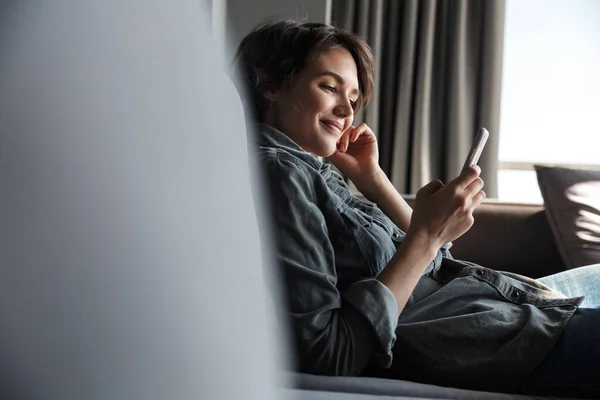 Kép Szép Fiatal Boldog Használja Mobiltelefon Mosolyog Miközben Kanapén Nappaliban — Stock Fotó