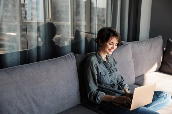 Bild Von Netter Junger Zufriedener Frau Mit Laptop Und Lächelnd — Stockfoto