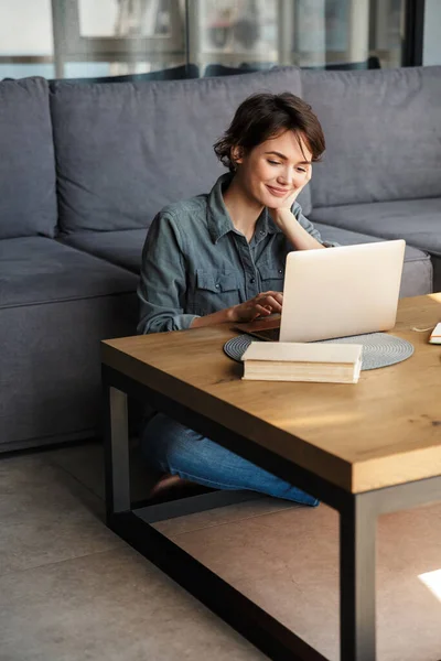 Imagem Jovem Mulher Alegre Agradável Usando Laptop Sorrindo Enquanto Sentado — Fotografia de Stock