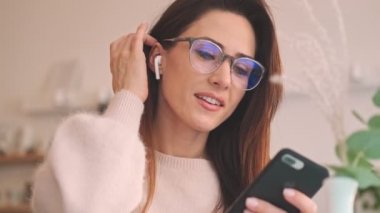 Hoş bir kafede oturan çekici bir kadının yakın çekim görüntüsü kulaklıklarını açıyor.