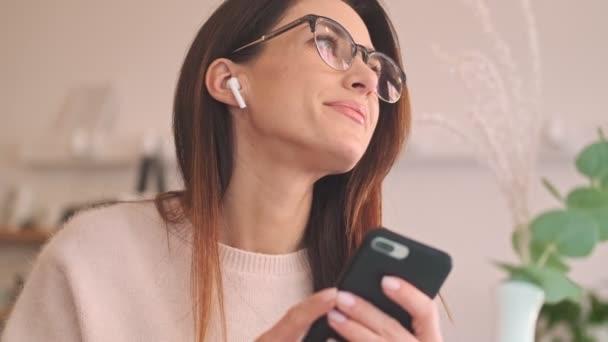 Eine Attraktive Frau Mit Ohrhörern Sitzt Mit Ihrem Smartphone Gemütlichen — Stockvideo