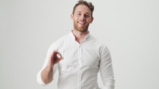 Jóképű fiatal elégedett boldog férfi fehér ingben elszigetelt felett fehér fal háttér