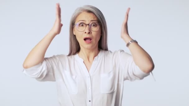 Zszokowana Dojrzała Kobieta Długimi Siwymi Włosami Okularach Ściska Głowę Białym — Wideo stockowe