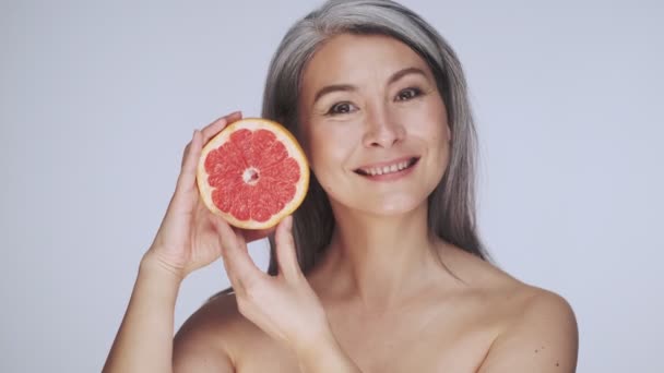 Krásná Stará Zralá Polonahá Žena Dlouhými Šedými Vlasy Pózuje Grapefruitem — Stock video
