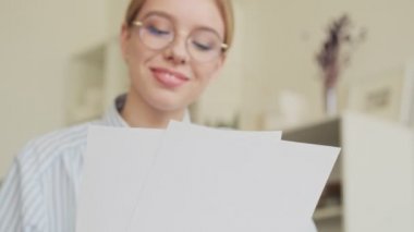 Mutlu gülümseyen başarılı genç bir mimar işyerinde kağıt belgelerle çalışıyor.