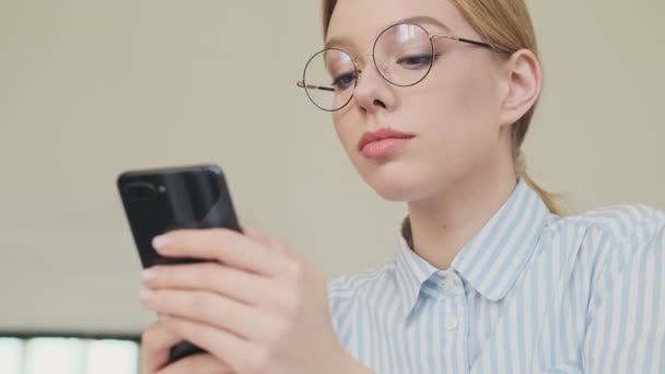 Eine Freundliche Junge Architektin Mit Brille Sitzt Mit Ihrem Smartphone — Stockvideo