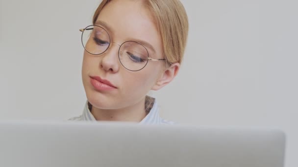 美しい若いブロンドの女性建築家が眼鏡をかけている彼女のラップトップで働いています彼女の現代的なオフィスに座って — ストック動画
