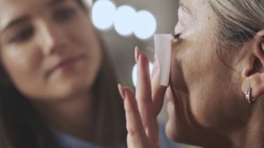 Güzellik salonunda makyaj sanatçısı olan yaşlı bir kadın müşterinin yakın çekimi.