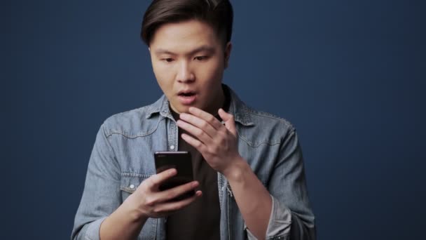 Ein Schockierter Junger Asiatischer Mann Bekommt Auf Seinem Smartphone Vor — Stockvideo