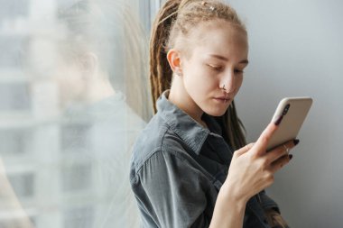 Rasta takmış ve cep telefonu kullanarak içeriyi delip geçen göz kamaştırıcı bir genç kız resmi..