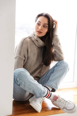 Pencere pervazında bacak bacak üstüne atmış, yan yan bakan Asyalı genç bir kadın.